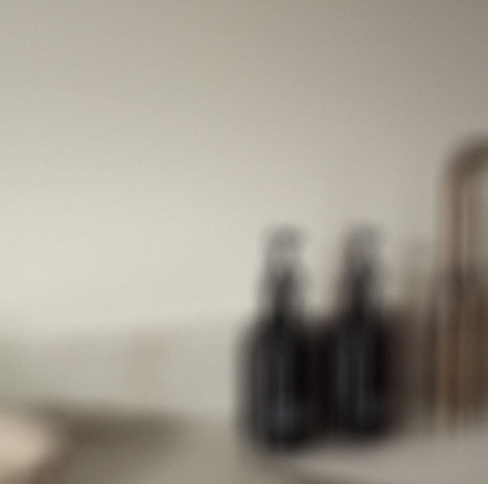 two black body-wash bottles standing next to a golden sink, beautifully dispalyed in a hotel.